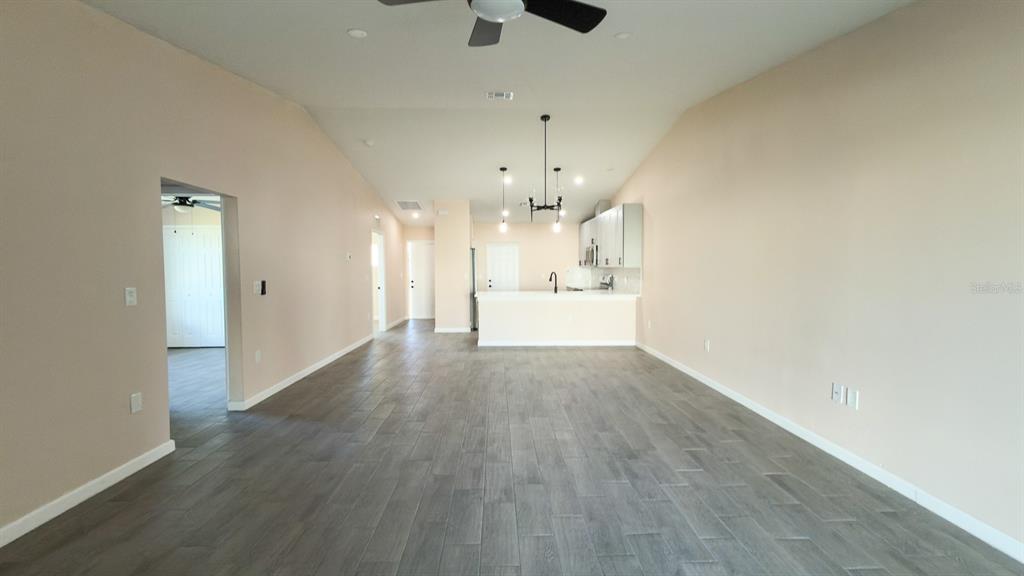 11154 Pendleton Avenue Englewood, FL 34224 - Photo 30 of 32 an empty room with wooden floor an empty space and a kitchen view