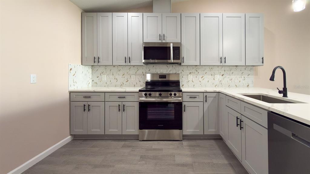 11154 Pendleton Avenue Englewood, FL 34224 - Photo 3 of 32 a kitchen with granite countertop white cabinets and stainless steel appliances