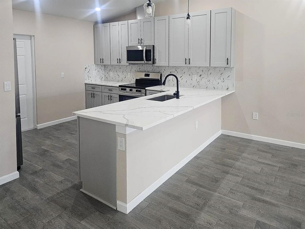 11154 Pendleton Avenue Englewood, FL 34224 - Photo 10 of 32 a kitchen with stainless steel appliances a sink stove and cabinets