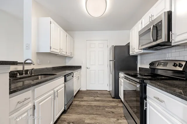 a kitchen with stainless steel appliances granite countertop a stove a sink and a microwave