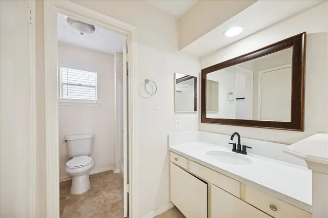 a bathroom with a toilet a sink a mirror and vanity