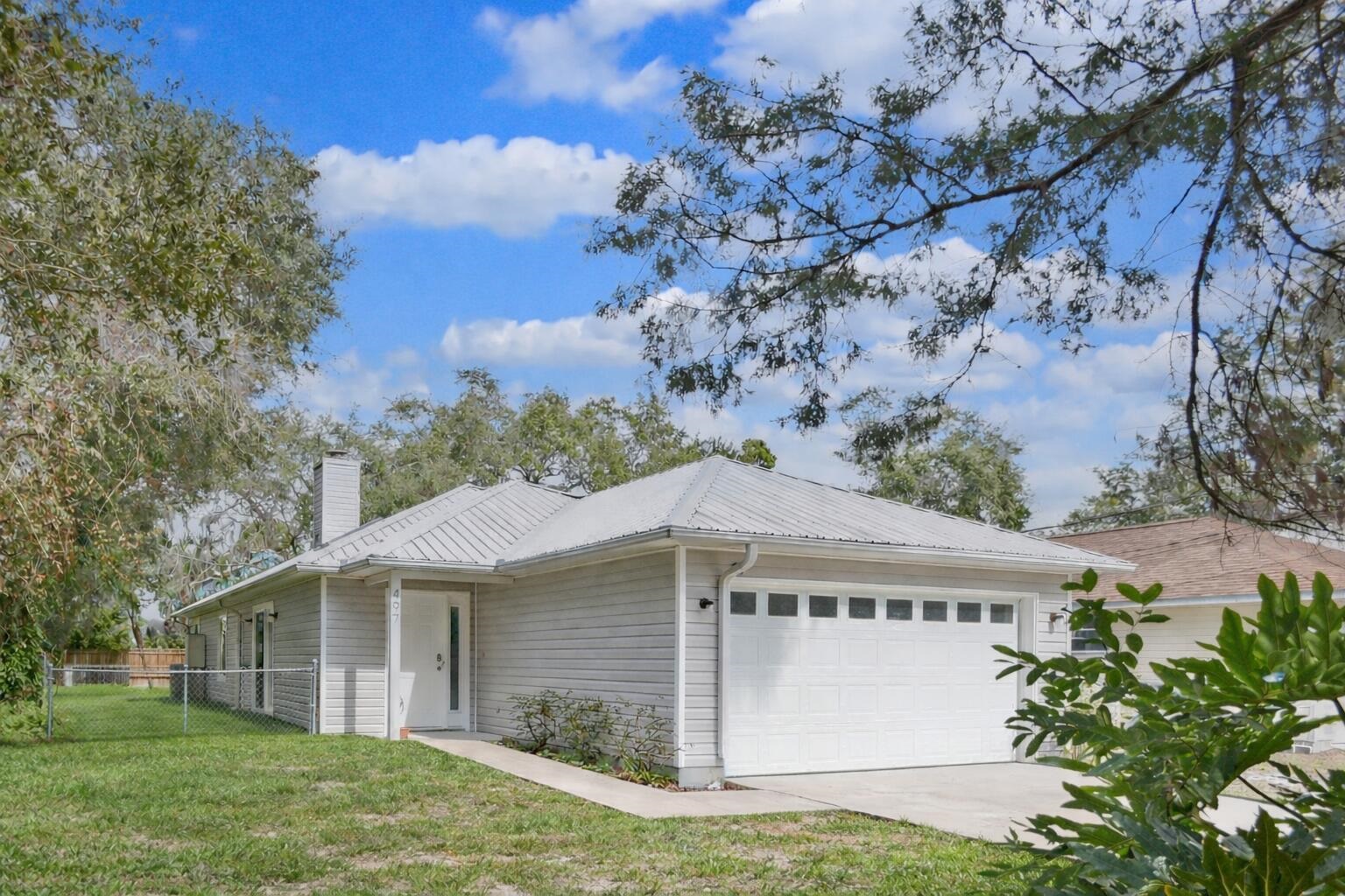 View of front of property with a metal roof, a garage, a chimney, and driveway