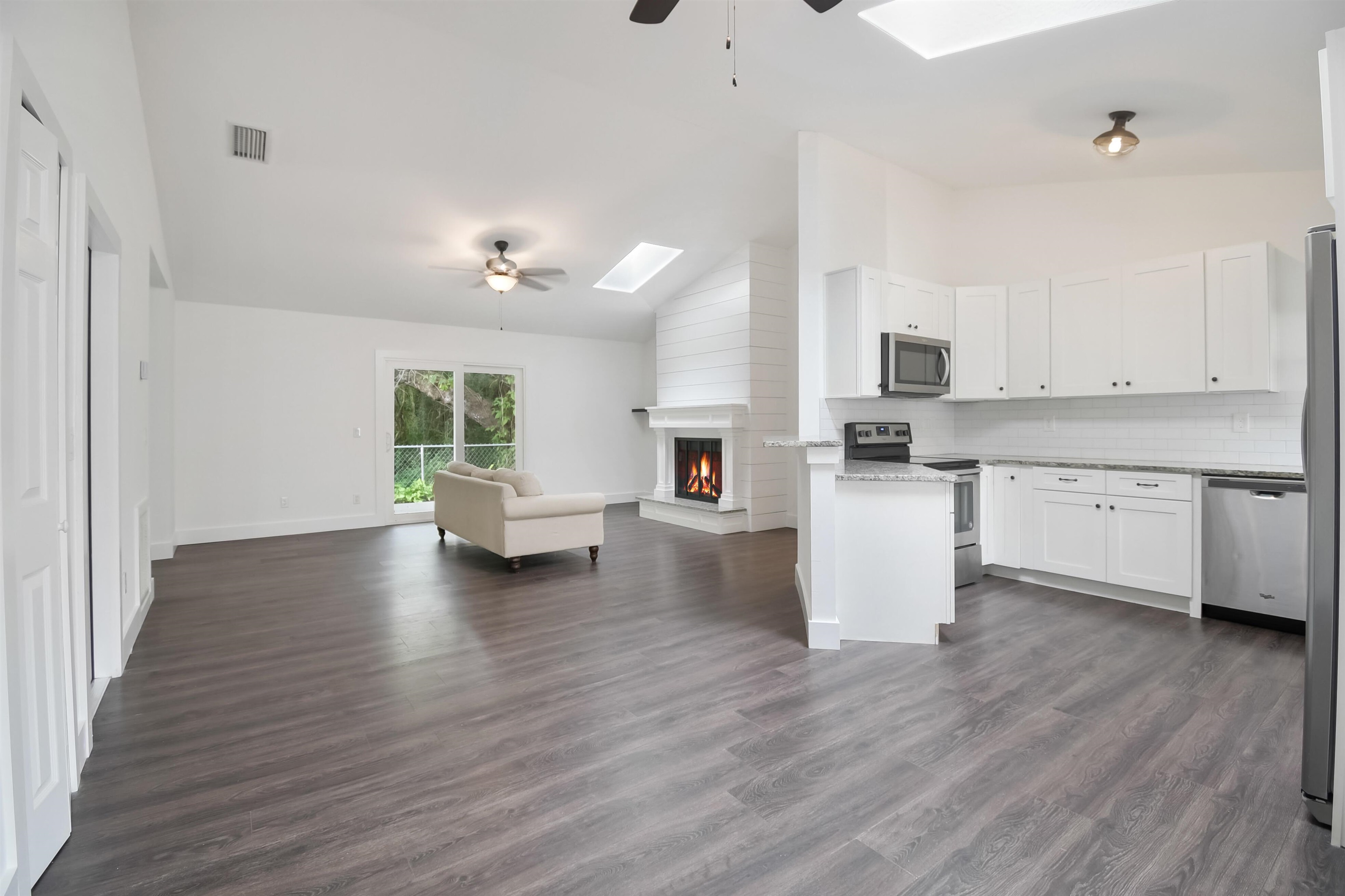 497 Pyrus Street St. Augustine, FL 32080 - Photo 36 of 36 Kitchen with a skylight, ceiling fan, open floor plan, vaulted ceiling, and white cabinets