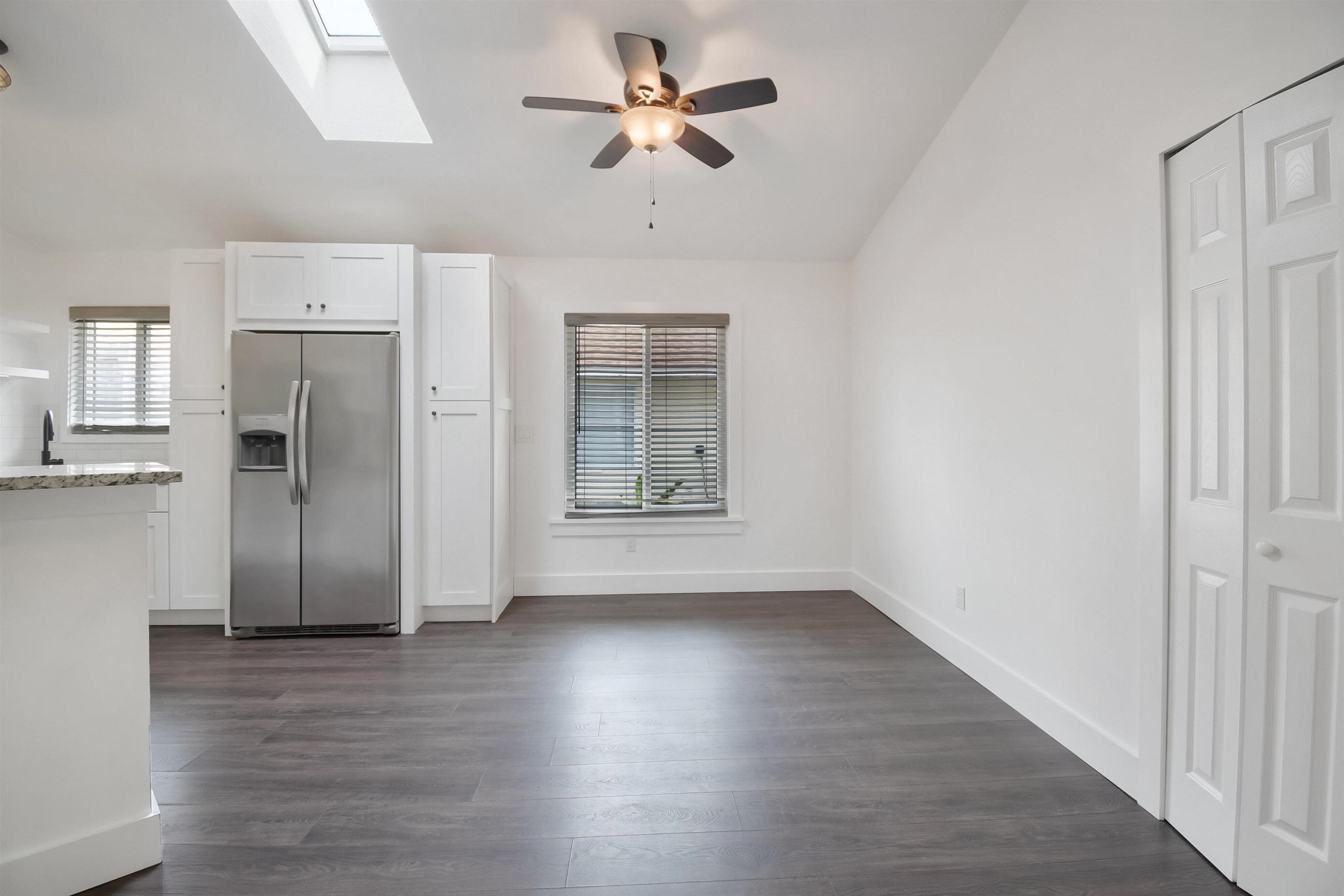 497 Pyrus Street St. Augustine, FL 32080 - Photo 6 of 36 Kitchen featuring a skylight, stainless steel fridge, white cabinets, dark wood finished floors, and light stone countertops