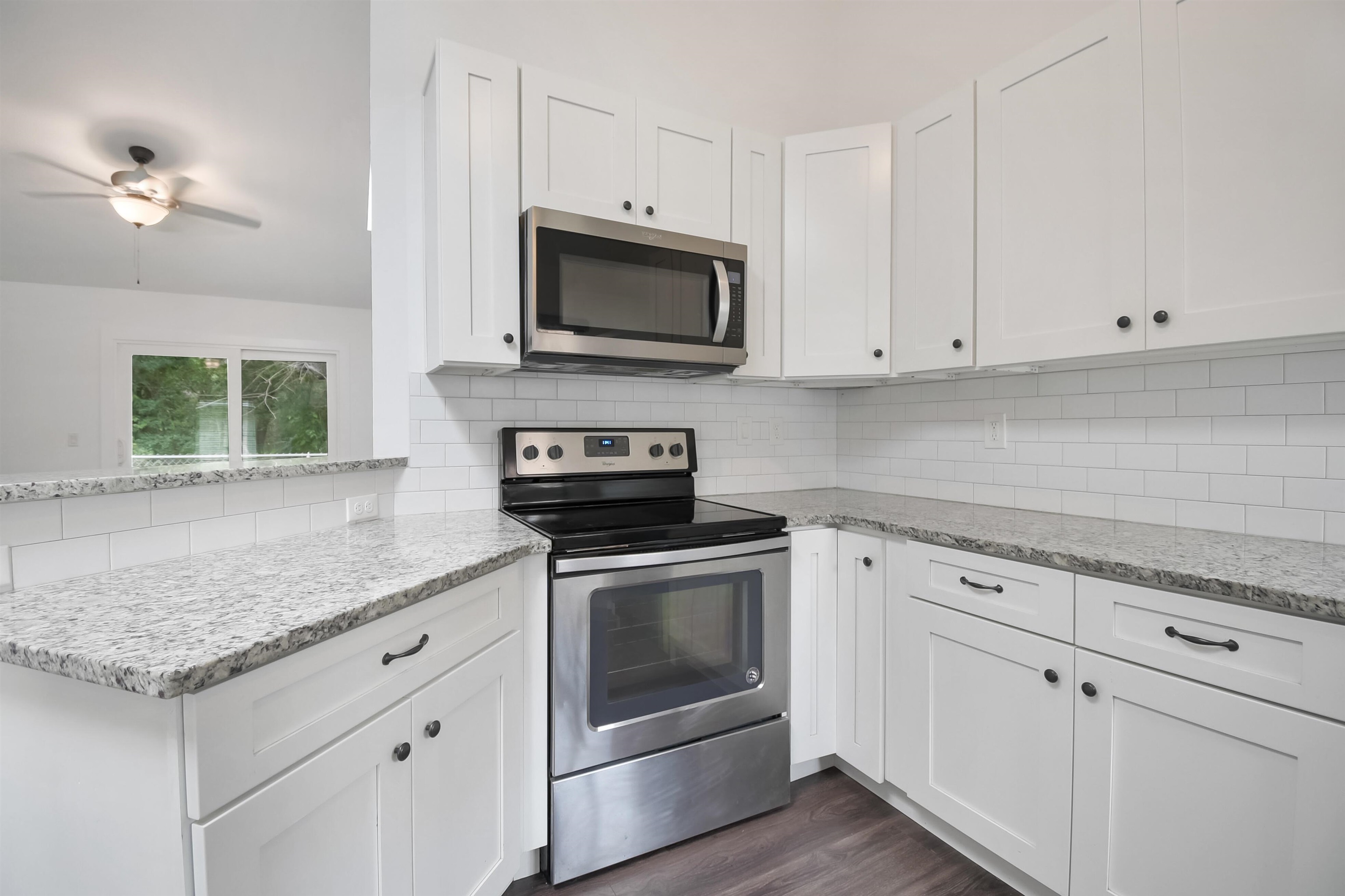 497 Pyrus Street St. Augustine, FL 32080 - Photo 9 of 36 Kitchen featuring stainless steel appliances, light stone counters, white cabinets, dark wood finished floors, and backsplash