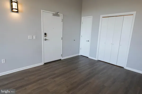a view of a livingroom with wooden floor and a refrigerator