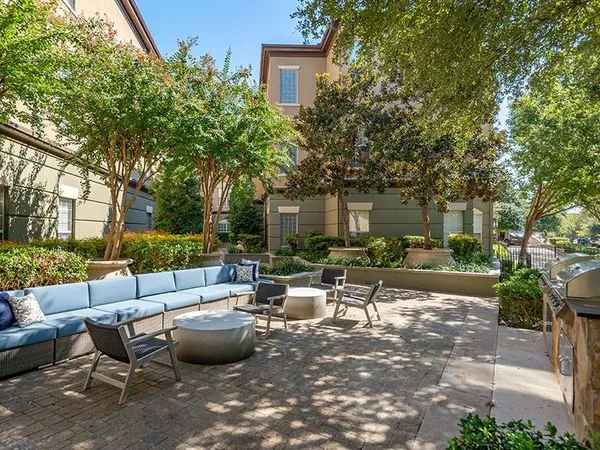 a view of a patio with couches and a fire pit and large trees
