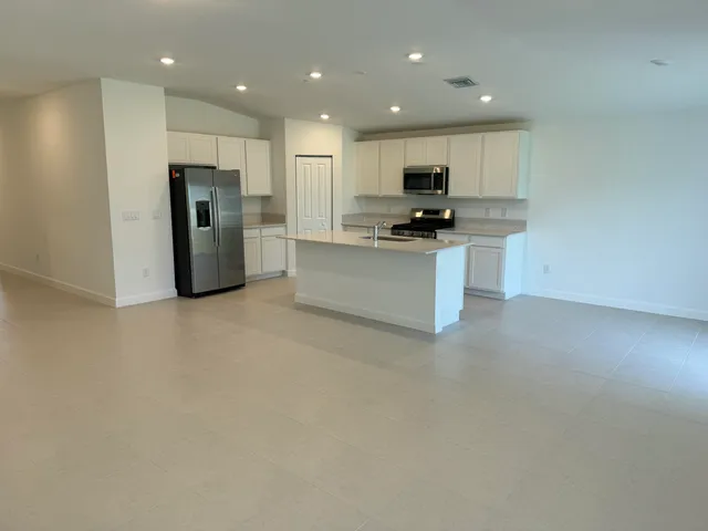 a kitchen with stainless steel appliances kitchen island granite countertop a refrigerator and a stove top oven