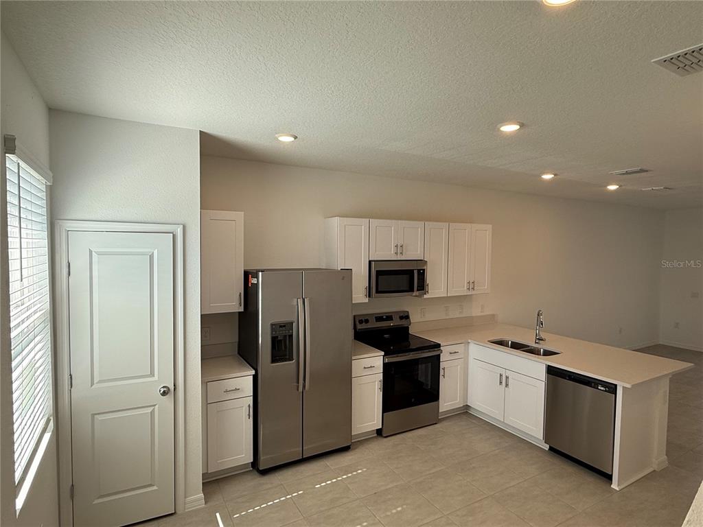 2980 Skyline Loop, Unit 2980 Kissimmee, FL 34758 - Photo 7 of 14 a kitchen with a refrigerator sink and white cabinets