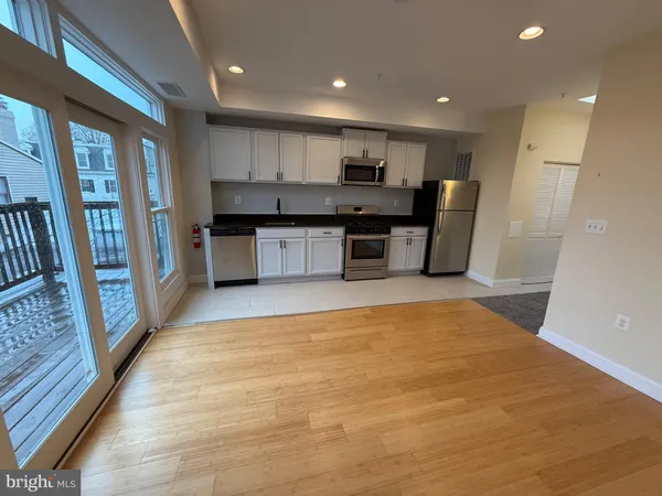 a large kitchen with stainless steel appliances a large counter top a stove a sink and a refrigerator