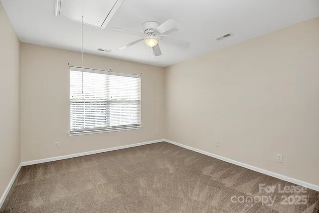 an empty room with chandelier fan and windows