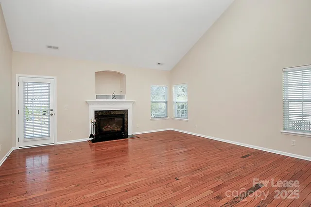 wooden floor fireplace and windows in an empty room