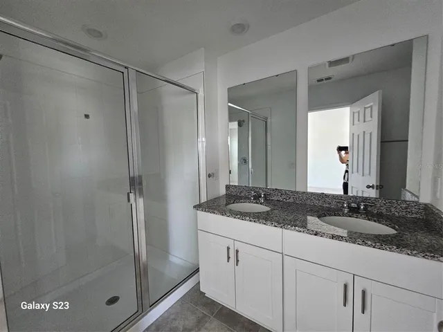 a bathroom with a granite countertop sink a mirror and a shower