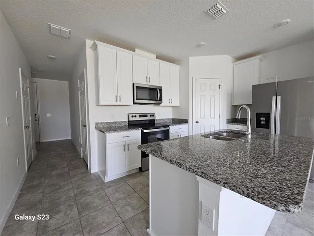 a kitchen with stainless steel appliances granite countertop a stove a sink a microwave a refrigerator and cabinets