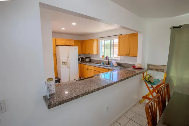 a large kitchen with granite countertop a sink a counter top space and living room area
