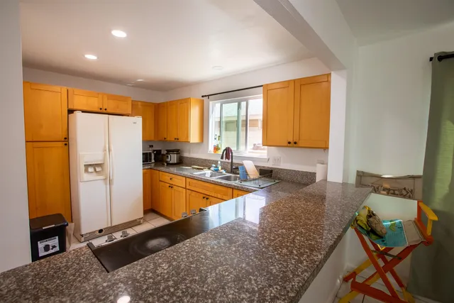 a large kitchen with granite countertop a refrigerator a stove a sink a dining table and chairs