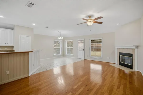 a view of empty room with wooden floor and fan