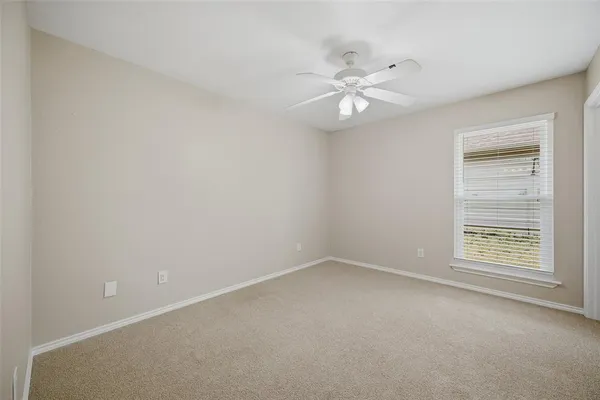 an empty room with a window and ceiling fan