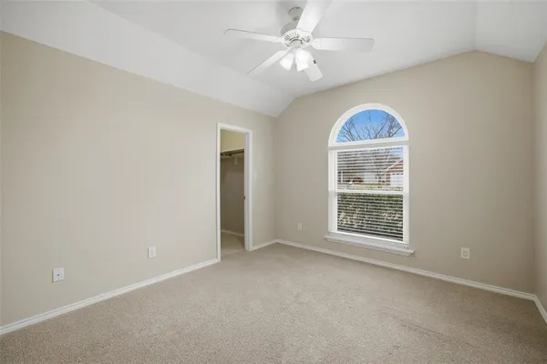 an empty room with chandelier fan and windows