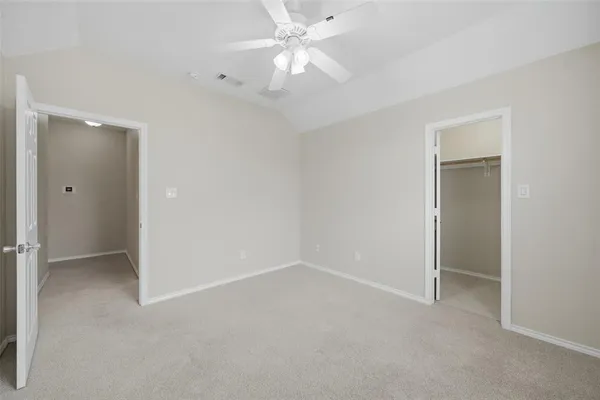 an empty room with closet and a ceiling fan