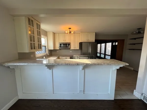 a kitchen with granite countertop a refrigerator a sink dishwasher a stove and white countertops with wooden floor