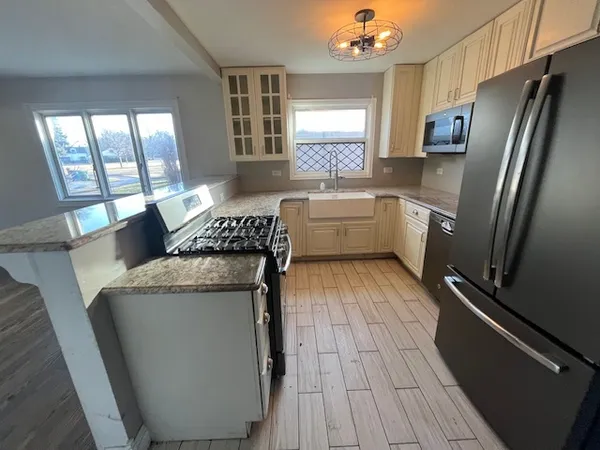 a kitchen with stainless steel appliances granite countertop a refrigerator a stove a sink and a microwave