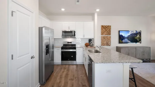 a kitchen with stainless steel appliances granite countertop a refrigerator a stove and a sink with wooden floor