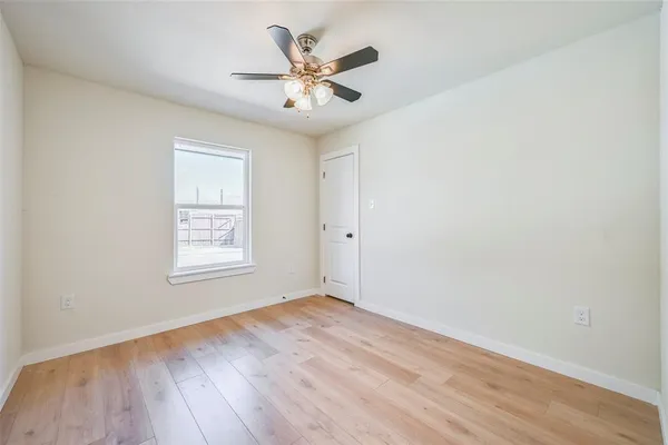 an empty room with wooden floor and ceiling fan