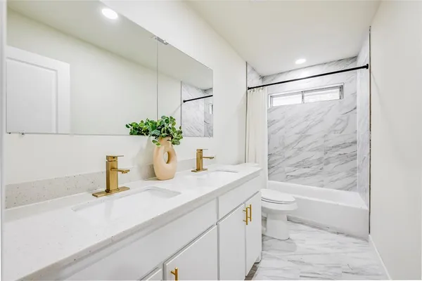 a bathroom with a granite countertop sink a toilet and shower