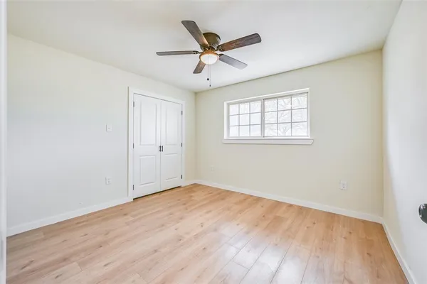 an empty room with wooden floor ceiling fan and windows