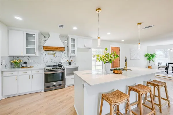 a kitchen with stainless steel appliances granite countertop a sink a stove and a wooden floors