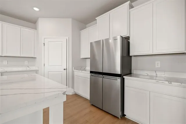 a kitchen with stainless steel appliances granite countertop a sink a stove a microwave a refrigerator a white cabinets and wooden floor