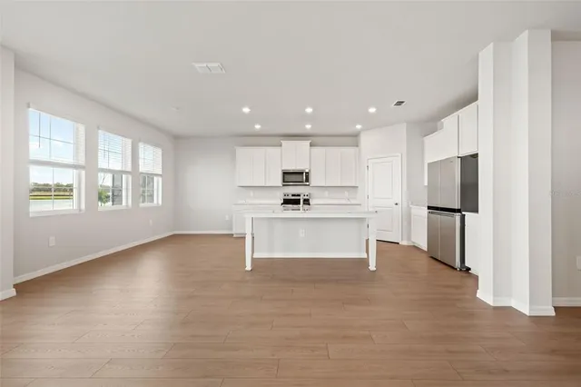 a kitchen with granite countertop white cabinets stainless steel appliances and wooden floor