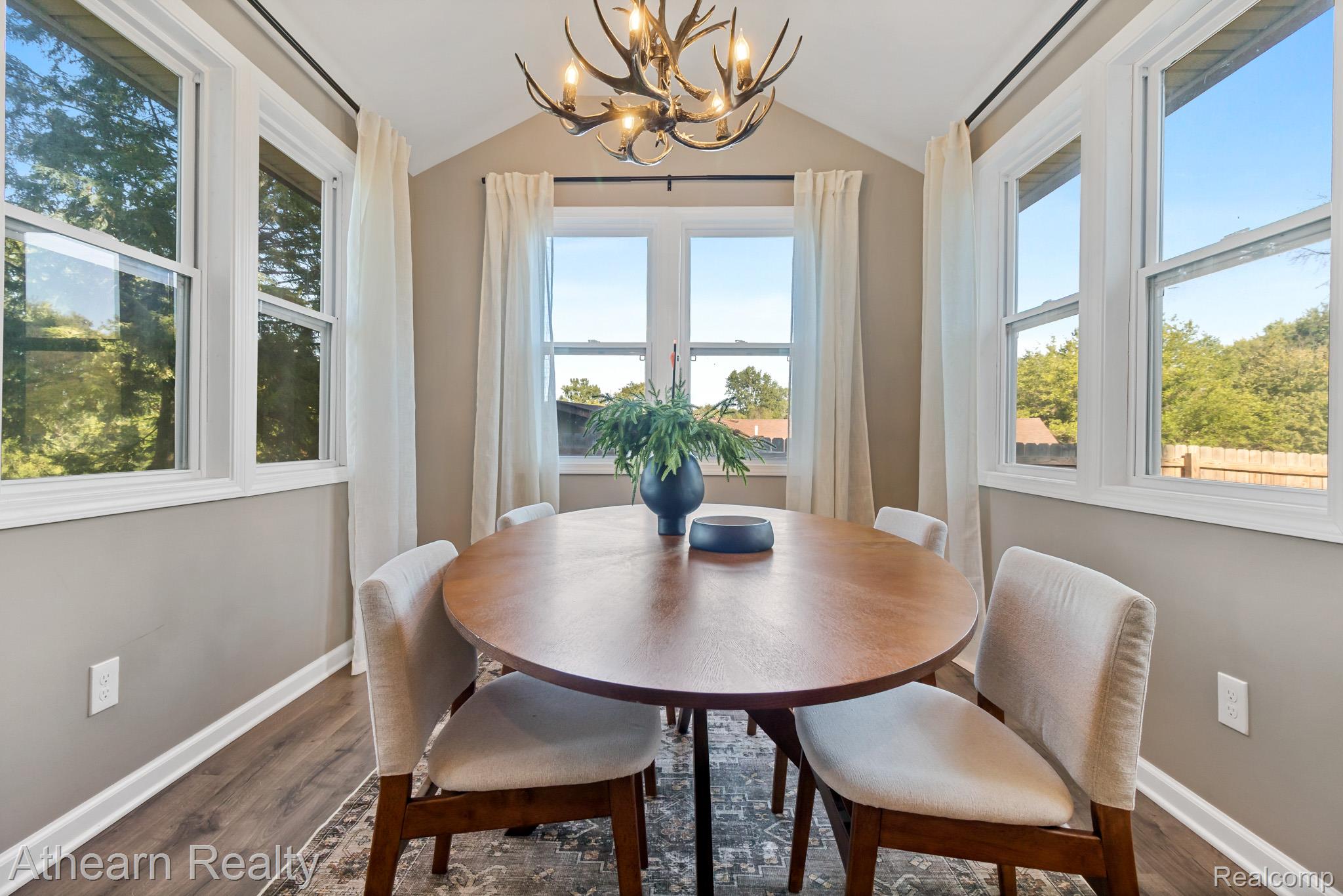5079 West Thompson Road Linden, MI 48451 - Photo 14 of 27 Elegant dining room bathed in natural light through multiple windows and glass doors framing scenic outdoor vistas