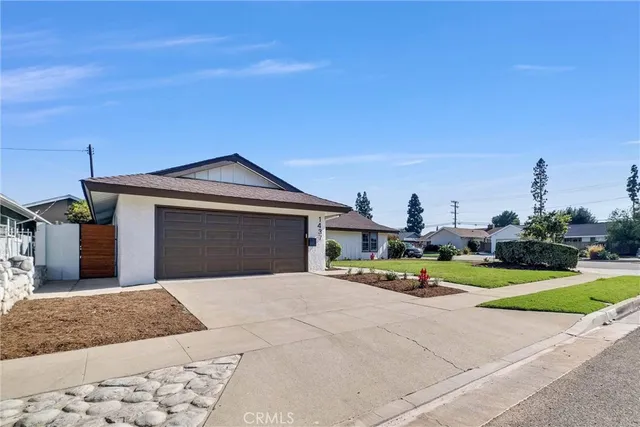 a view of a house with a small yard and a large tree