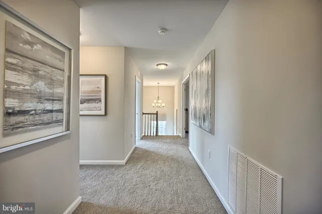 a view of a hallway with wooden floor and a bathroom