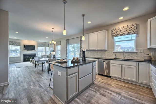 a kitchen with stainless steel appliances granite countertop a stove top oven a sink a dining table and chairs with wooden floor