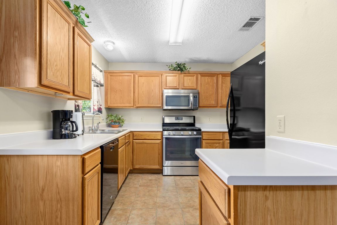 2158 Redwing Way Round Rock, TX 78664 - Photo 7 of 25 a kitchen with stainless steel appliances granite countertop a sink dishwasher stove top oven and refrigerator