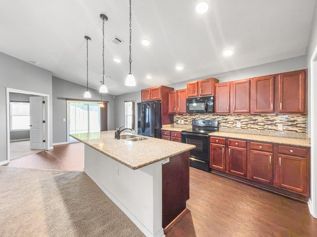 125 Lillian Way Crestview, FL 32536 - Photo 7 of 33 a large kitchen with kitchen island a stove a sink a center island and wooden cabinets