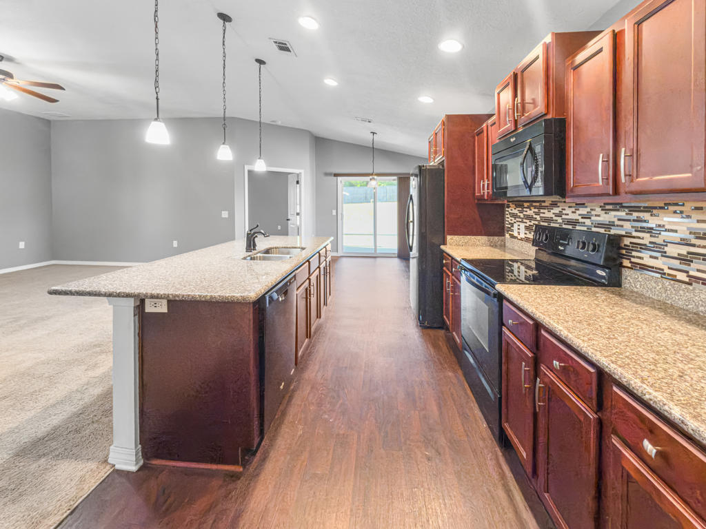 125 Lillian Way Crestview, FL 32536 - Photo 8 of 33 a large kitchen with stainless steel appliances granite countertop plenty wooden cabinets counter space a sink and wooden floor