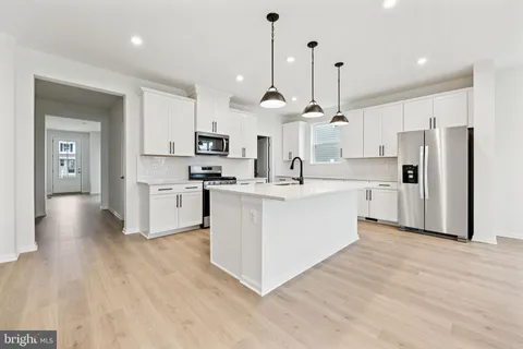 a large white kitchen with cabinets a refrigerator a sink and a stove