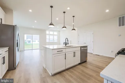 a kitchen with stainless steel appliances granite countertop wooden floors sink and white cabinets