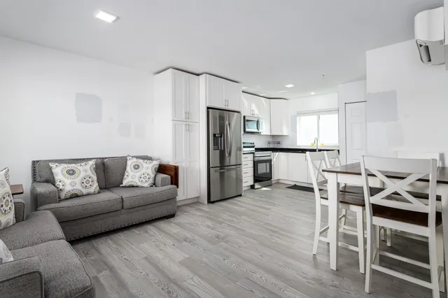 a living room with stainless steel appliances furniture cabinets and a wooden floor
