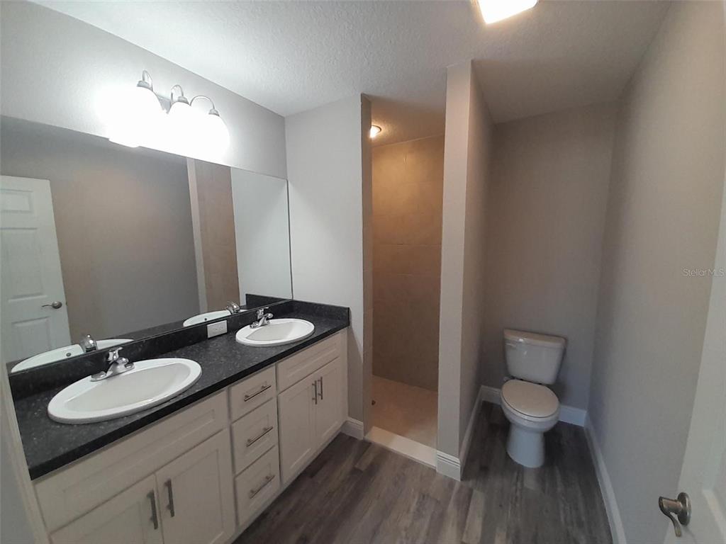 127 Malauka Road Ocklawaha, FL 32179 - Photo 10 of 11 a bathroom with a granite countertop sink a toilet a mirror and shower