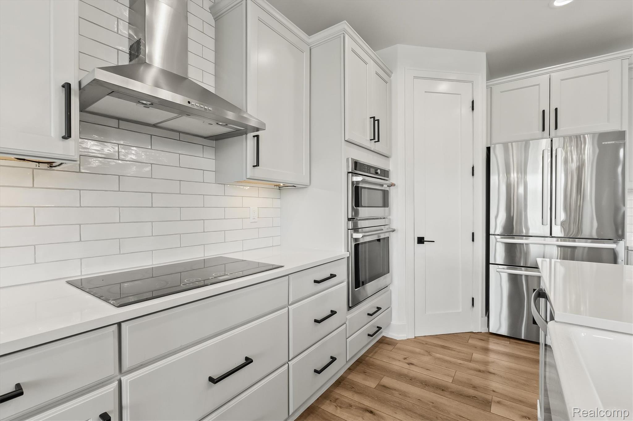 2554 Middleton Street Rochester, MI 48309 - Photo 16 of 38 Kitchen featuring light gray cabinetry with black hardware, white subway tile backsplash, stainless steel appliances, and wood-finish flooring