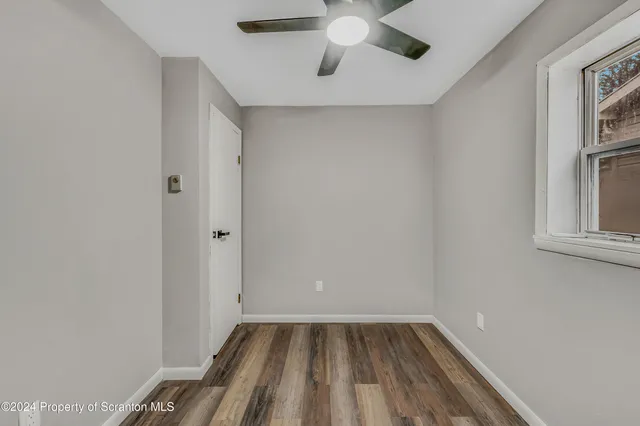 a view of an empty room with a window and wooden floor