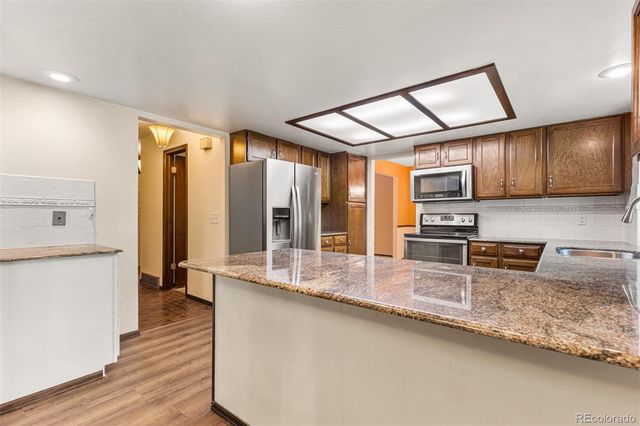 a kitchen with stainless steel appliances granite countertop a sink a stove and cabinets