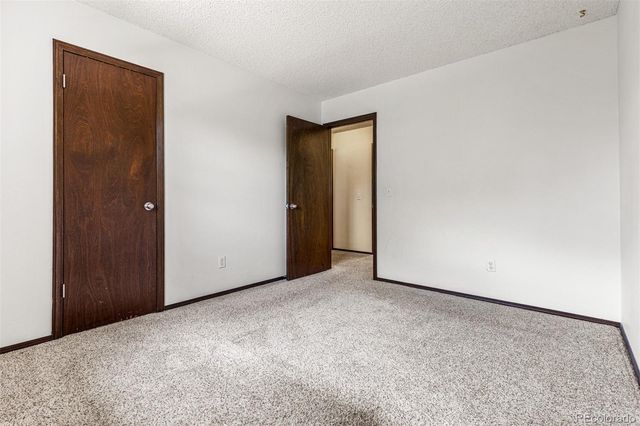 a view of an empty room with closet and a bathroom