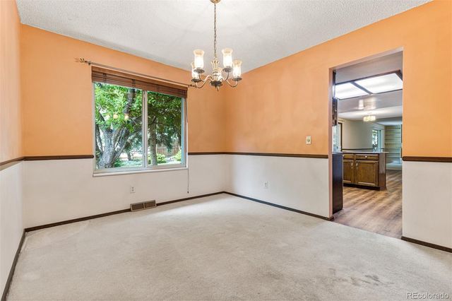 an empty room with chandelier fan and windows