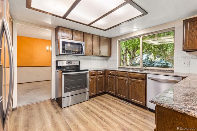 a kitchen with stainless steel appliances granite countertop a stove a sink and a refrigerator